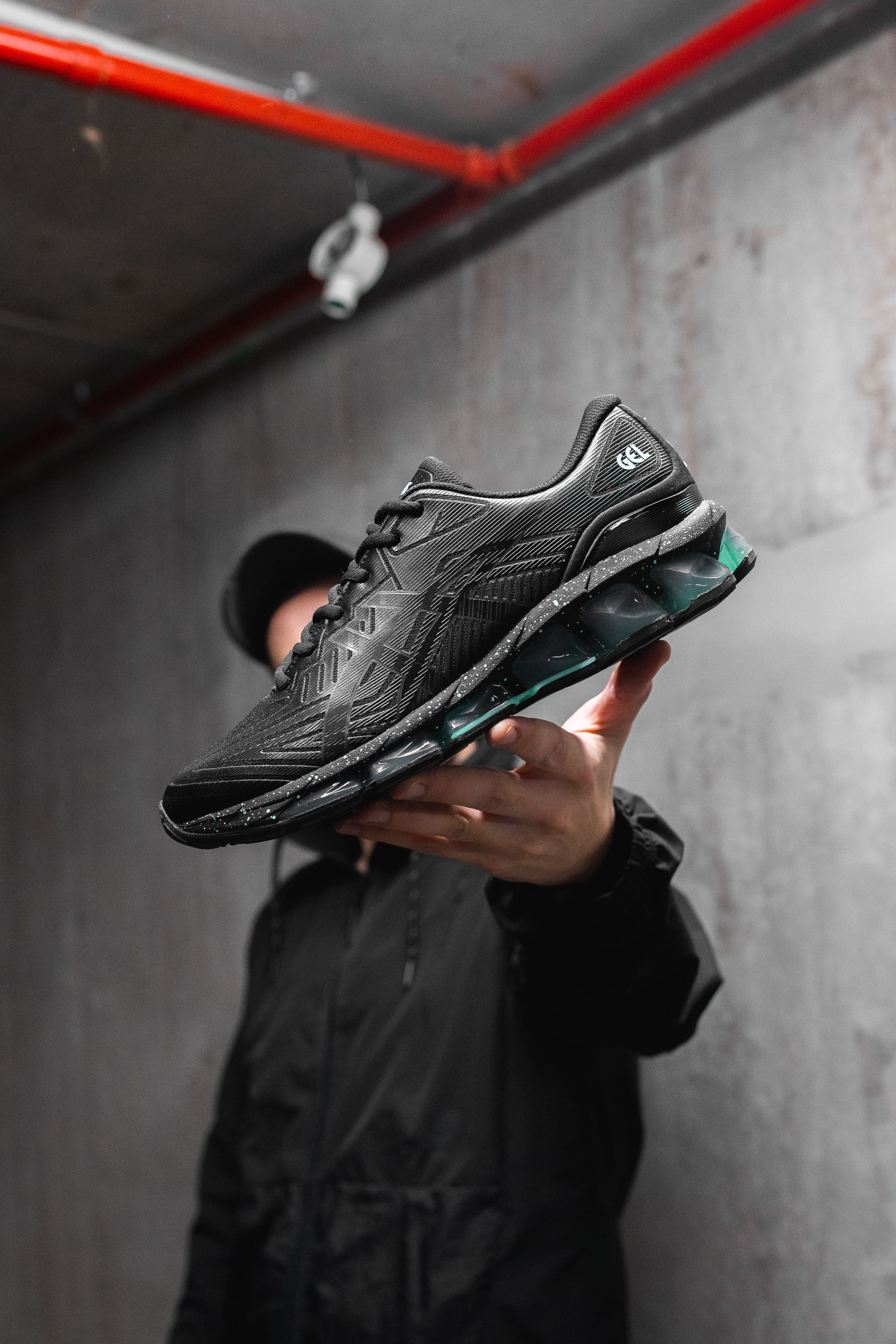 Photo of a black ASICS Gel Quantum 360 VII, with a black and green midsole held in a hand.