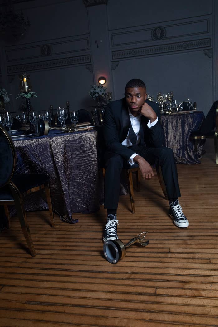 Vince Staples sitting on a chair with a trophy at his feet