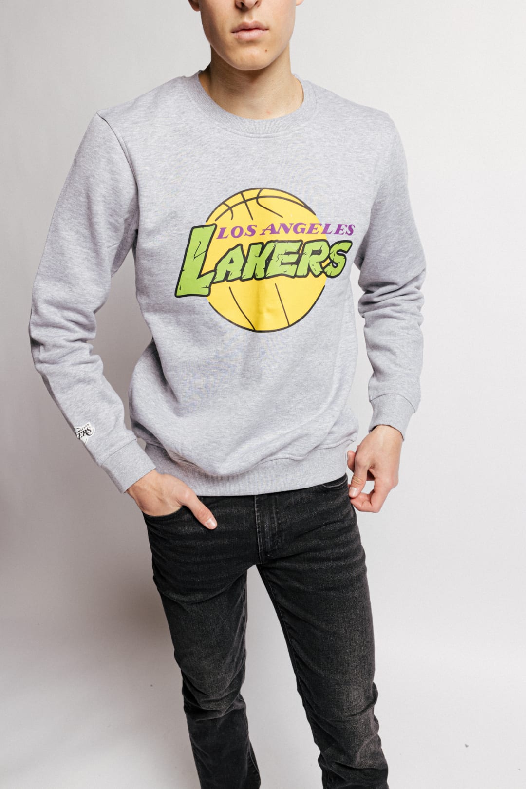 A model wearing a grey crewneck with the Lakers logo in a green TMNT font.