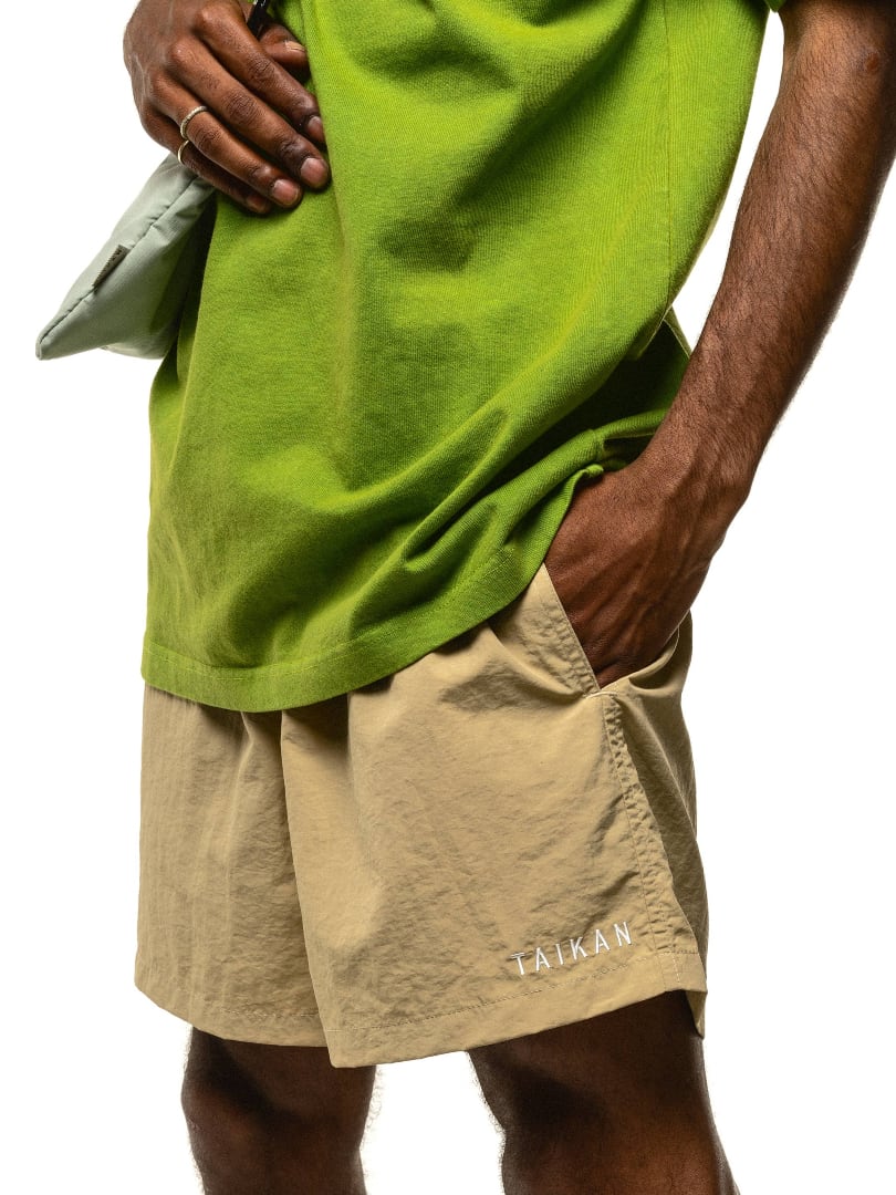 Model wearing tan shorts and a green shirt.