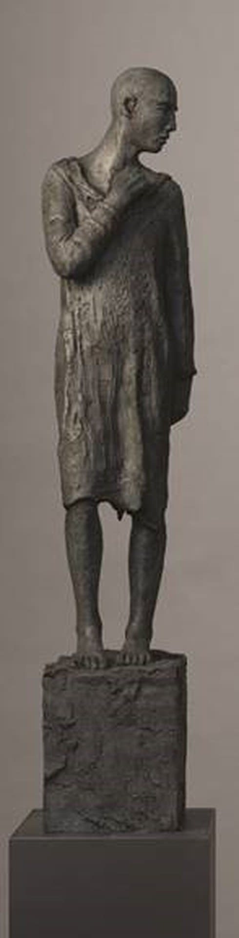 A bronze, androgynous statue looking to its left.