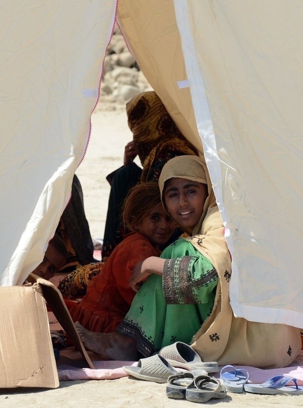 Survivors sit in a tent near their collapsed mud houses in the earthquake-devastated district of Awaran.