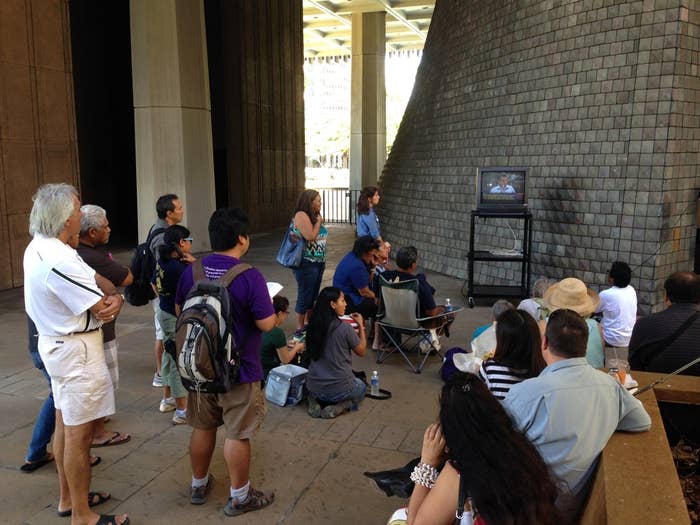 People watch the joint committees hearing on TV from the Hawaii State Capitol rotunda Monday.