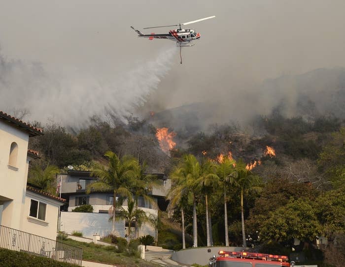 A helicopter drops water as firefighters battle the Colby Fire.