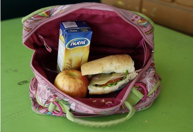 A student's lunch box brought from home sits on display at an elementary school in Quito. It's a ham sandwich with cheese, tomato and lettuce, a boxed oatmeal drink, and an apple.