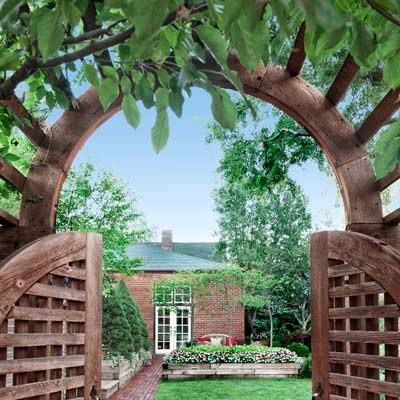 Mark entrances to secret gardens and create Instagram-worthy vignettes with a garden arbor. Shown here, an arched arbor covered in rambling wisteria marks the entry to a backyard from a back alley.