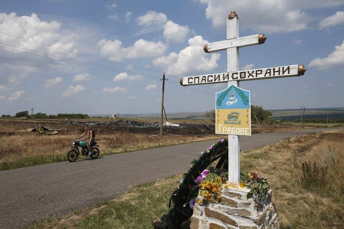 A local resident rides past near the village sign opposite the wreckage of Malaysia Airlines MH17.