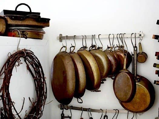 Works especially well if you don't want to hang the pots above your head. From here. (Collection of perfectly tarnished cookware optional. This works just as well for your cheapo pots and pans).