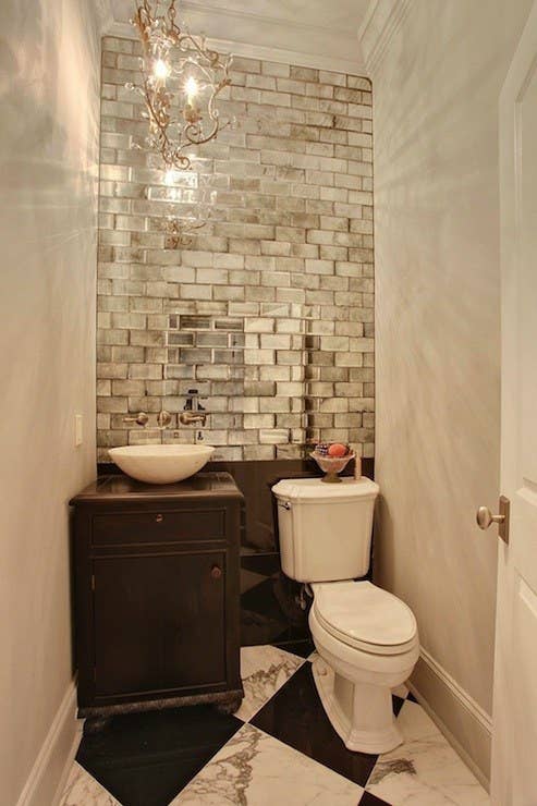 Mirrors can instantly double the appearance of a room, but there's no reason you have to go the traditional route! Metallic subway tile adds a layer of texture to this tiny WC.