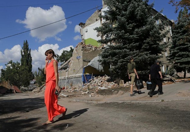 A woman on a cellphone walks past a building destroyed by shelling in Snizhne, Donetsk region, on Aug. 29.