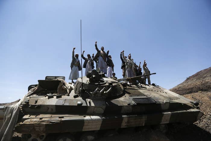 Houthi fighters gesture as they stand atop an army vehicle they took from the compound of the army's First Armoured Division in Sanaa.