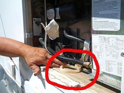 Man putting cut up flea collar near propane tank of RV