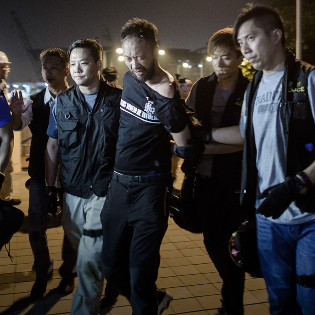 Protester Ken Tsang being led off by police officers before being beaten.