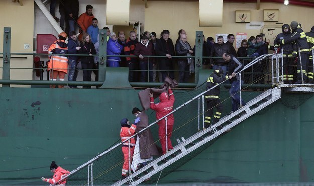 A passenger is helped as he leaves from a cargo container ship after arriving in Bari harbour, after the car ferry Norman Atlantic caught fire in waters off Greece.