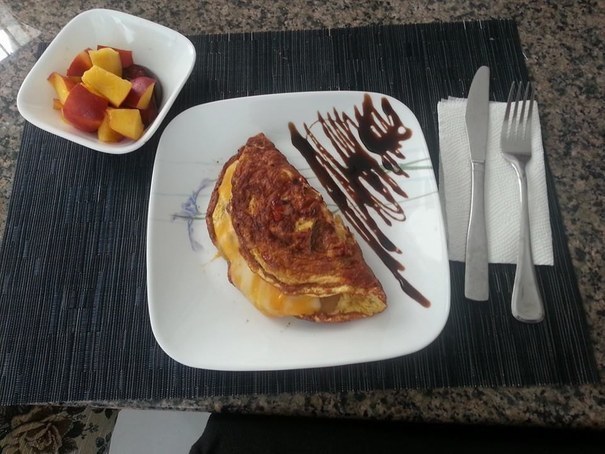 "Zucchini, onion, red pepper, ham, and cheddar omelet with a balsamic reduction drizzle on the side. And a side of chopped stone fruit."