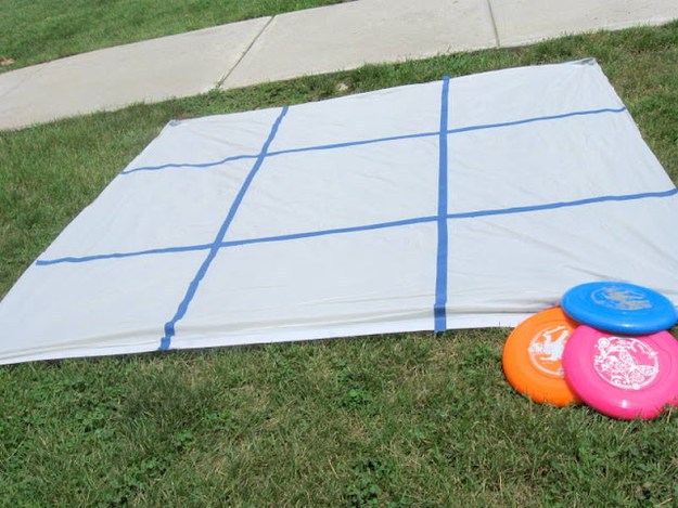 DIY this backyard tic-tac-toe game with a shower curtain, tape, and Frisbees.