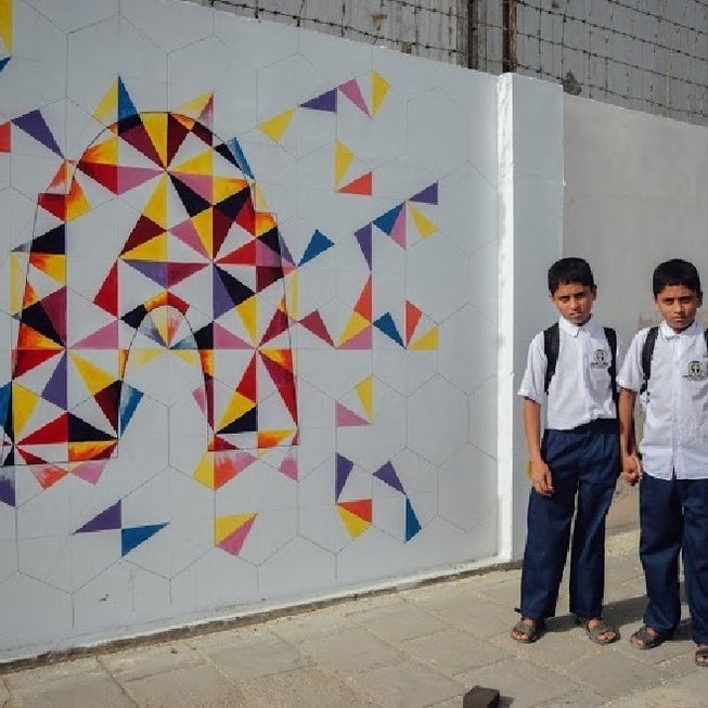 Children stand beside a geometric drawing of Mazar-e-Quaid, the tomb of Muhammad Ali Jinnah, the founder of Pakistan.