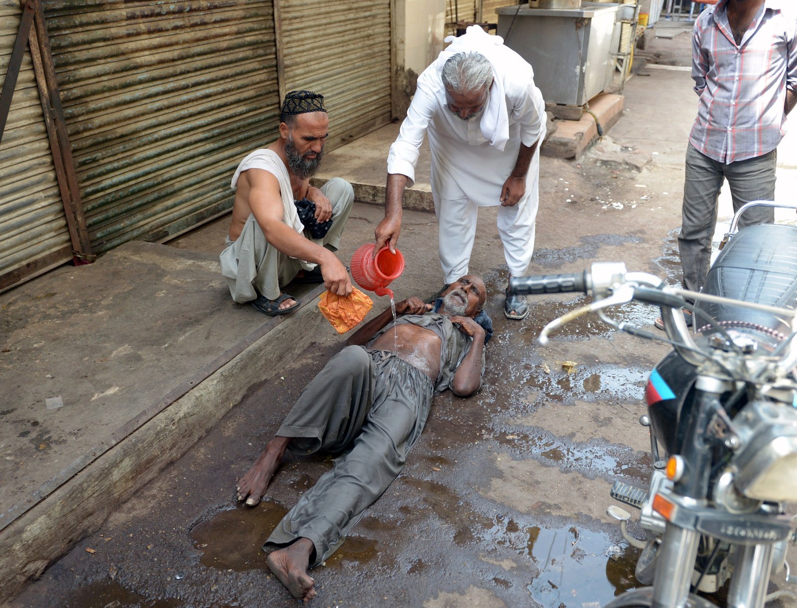 A Pakistani resident helps a heatstroke victim at a market area during a heatwave in Karachi on June 23, 2015. The death toll from a heatwave in southern Pakistan passed 450 as medics battled to treat victims after imposing a state of emergency in hospitals, health officials said.