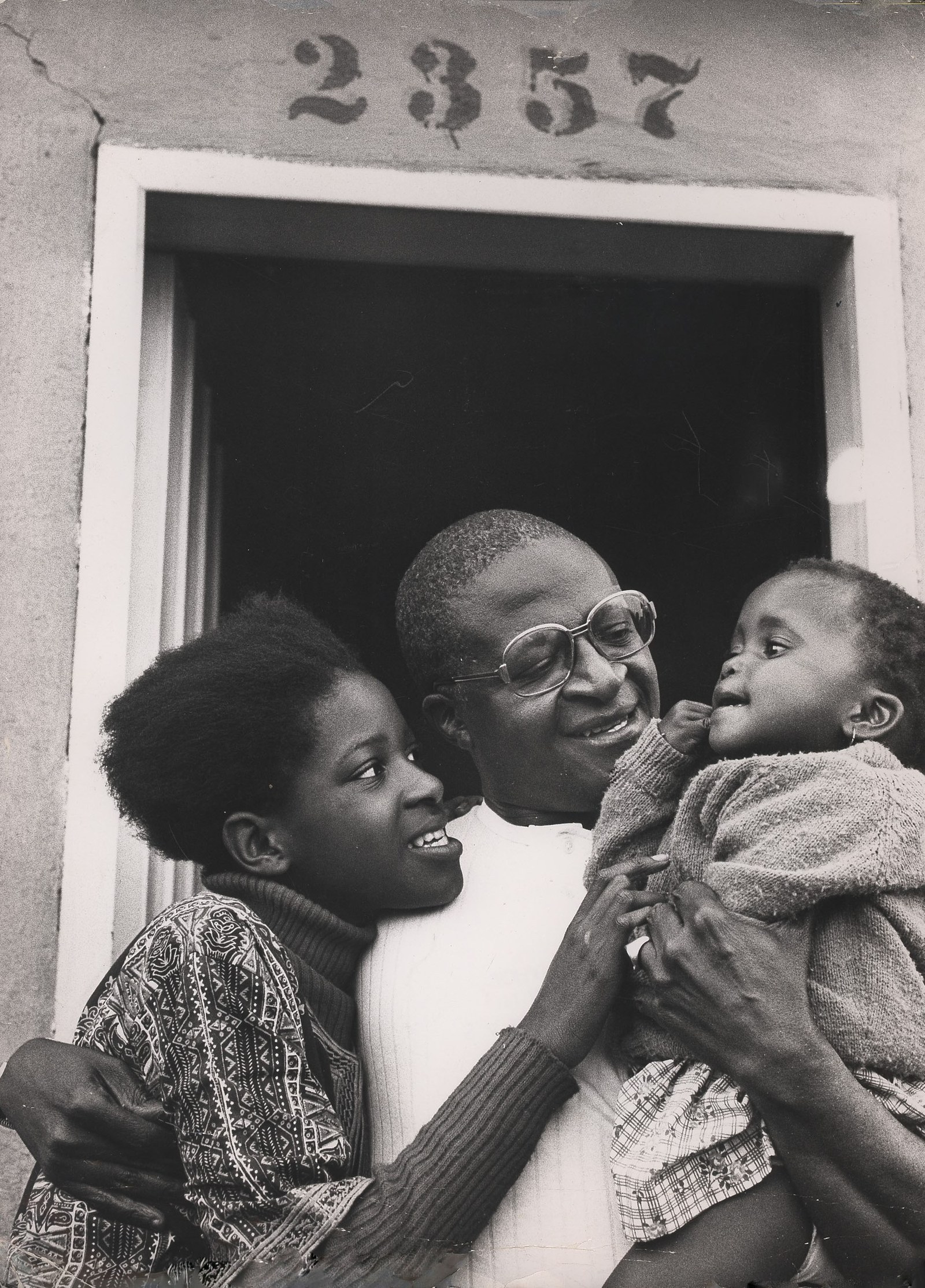 Tutu hugging two children in a doorway