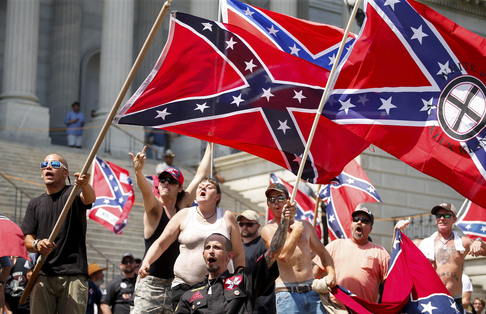 Members of the Ku Klux Klan yell as they fly Confederate flags during a rally at the statehouse in Columbia, South Carolina. A Ku Klux Klan chapter and an African-American group planned overlapping demonstrations on Saturday outside the South Carolina State House, where state officials removed the Confederate battle flag last week.