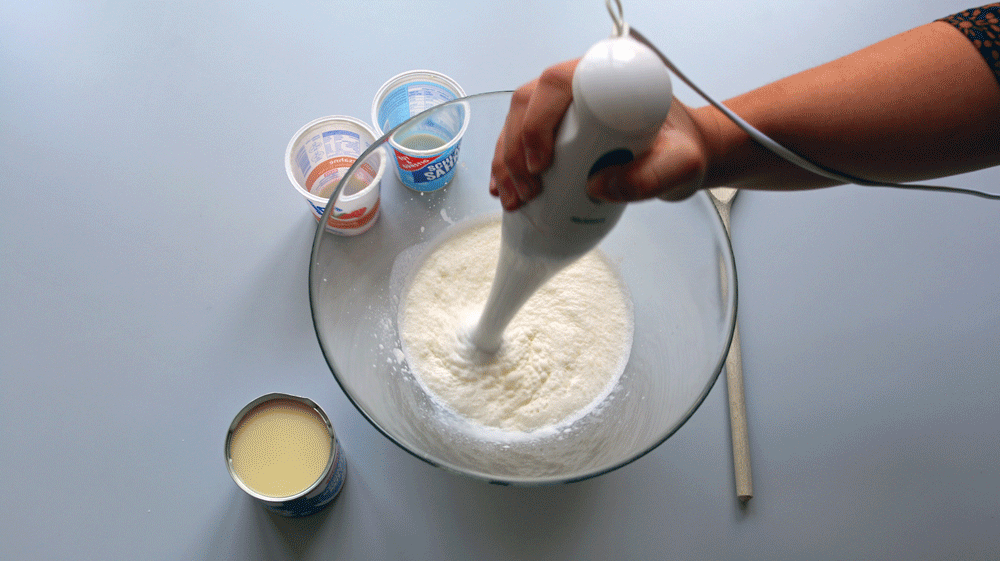 Wenn Du keinen Mixer hast - kein Problem. Die Sahne sollte nicht mehr komplett flüssig sein, damit sie sich besser mit der gezuckerten Kondensmilch vermischen lässt. Ein Schneebesen reicht vollkommen aus, Du musst die Sahne nicht komplett steif schlagen. Je flüssiger die Konsistenz, desto länger dauert es aber, bis das Eis gefroren ist. Wenn die Sahne aufgeschlagen ist, einfach die gezuckerte Kondensmilch dazu geben und vorsichtig verrühren, so dass die Sahne die Konsistenz behält.