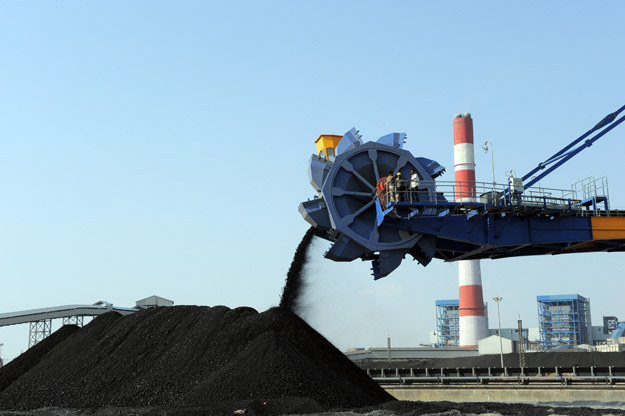 Workers use heavy machinery to sift through coal at the Adani Power company thermal power plant in India.