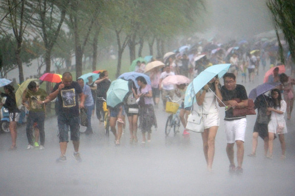 People use umbrellas as they walk in strong wind and heavy rain in Hangzhou, China, on Aug. 7.