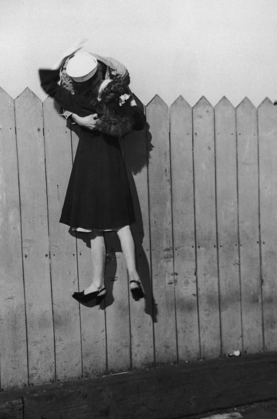Un marin se penche au-dessus d&#x27;une palissade et soulève sa petite amie pour l&#x27;embrasser. 1945.