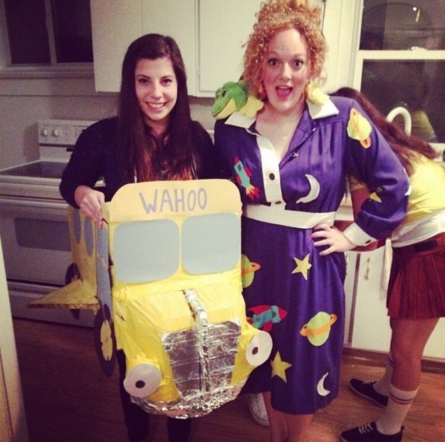 Woman dressed as a school bus and woman in a purple dress with a lizard on her shoulder