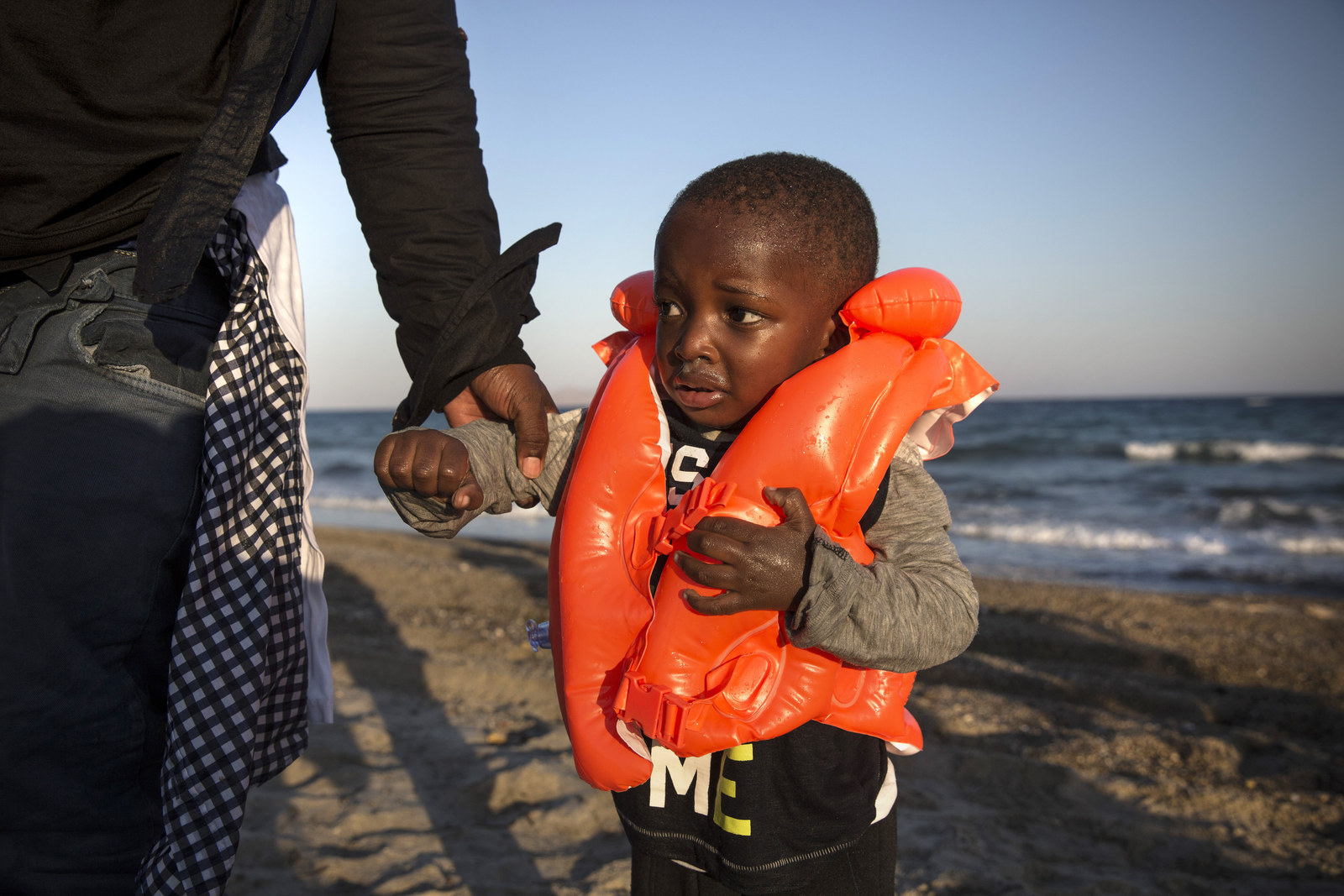 A young child is helped to shore after arriving on a beach in an inflatable boat in Kos, Greece. Migrants from many parts of the Middle East and African nations continue to flood into Europe before heading from Athens, north to the Macedonian border. Since the beginning of 2015, the number of migrants using what's called the 'Balkans route' has exploded, marking the largest migration of people since World War II.