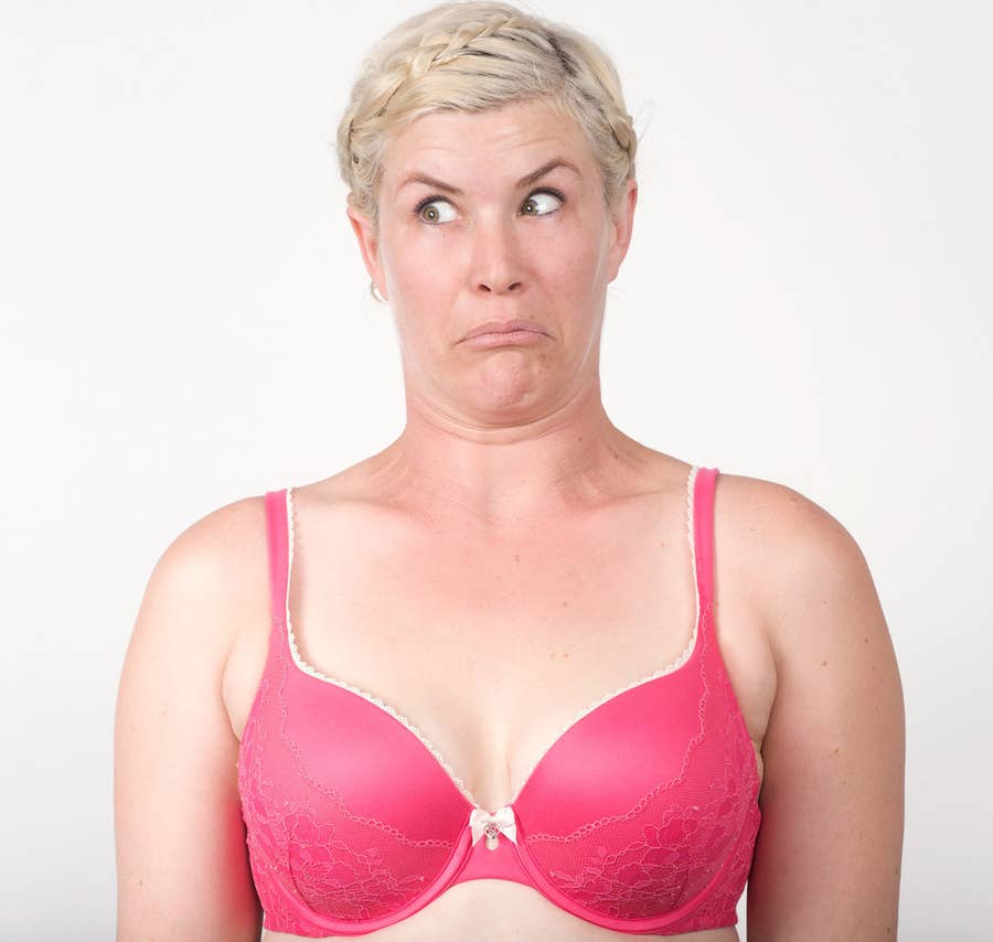 Fat woman with large breasts in a push-up bra on pink background