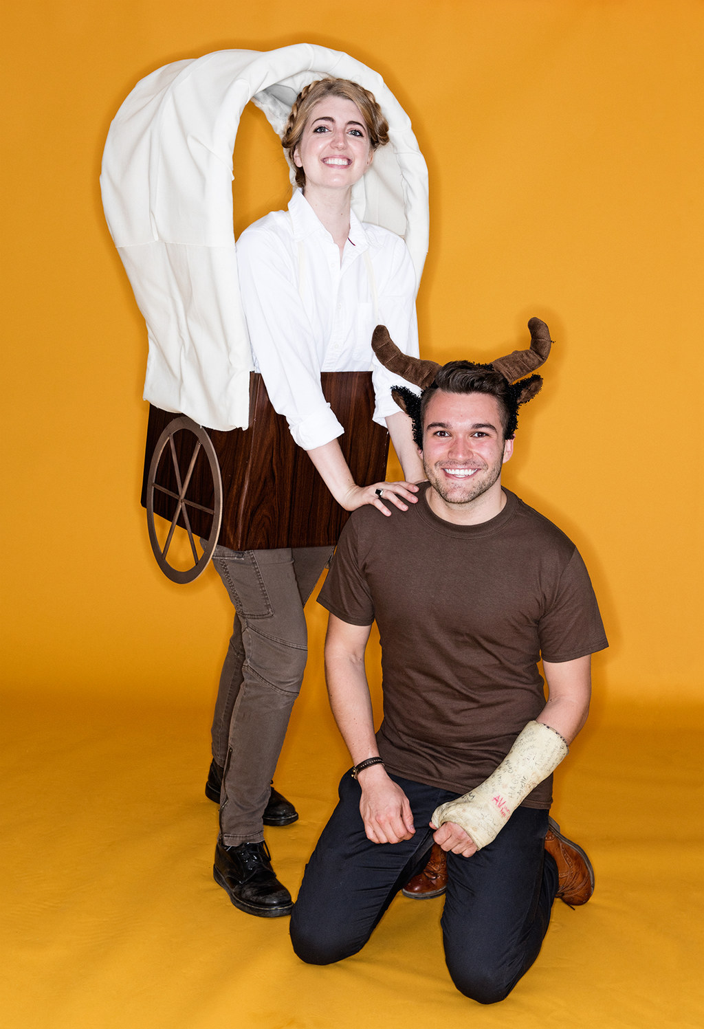 Woman in a wagon costume next to a man on his knees and wearing horns