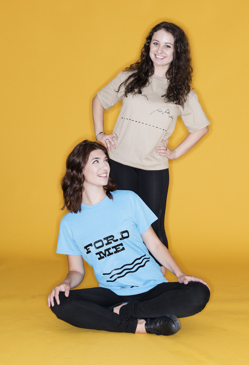 Seated woman wearing a &quot;Ford Me&quot; T-shirt next to a woman wearing a hilly T-shirt