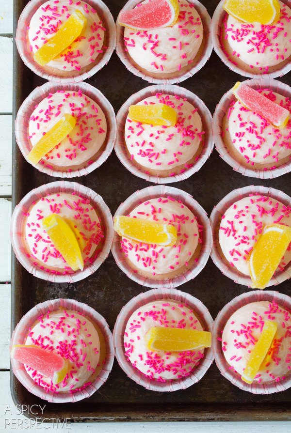 Top pink lemonade cupcakes with some citrus slice gummies and a smattering of sprinkles.