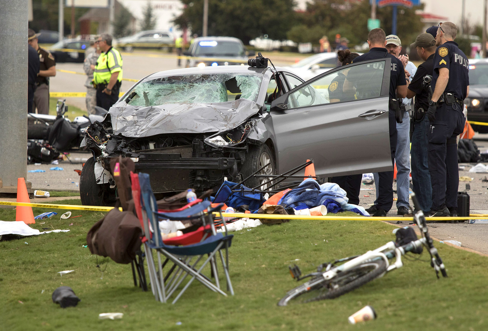 Emergency officials stand over wreckage after a suspected drunk driver crashed into a crowd of spectators during the Oklahoma State University homecoming parade in Stillwater, Oklahoma. The car slammed into a crowd, killing four and injuring at least 47 before the Kansas Oklahoma State football game.