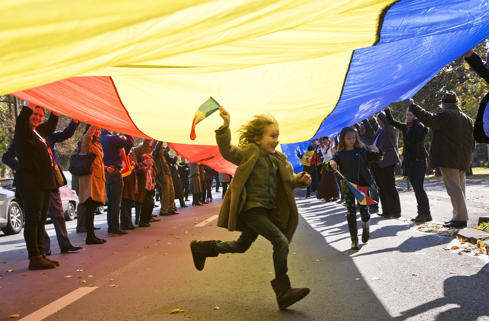 A child runs under a large flag, as supporters of the monarchy march to celebrate the 94th birthday of former Romanian King Michael I, in Bucharest, Romania. Monarchy supporters carried a 150 meters long flag on a main boulevard in the Romanian capital to celebrate the former king's birthday.