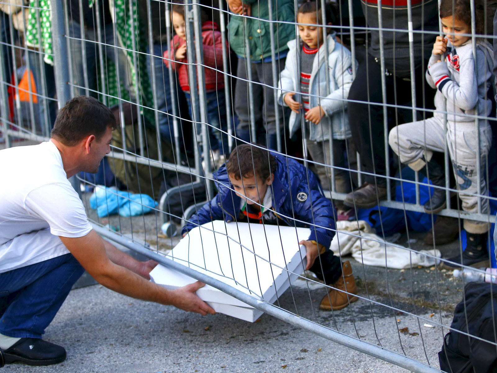 A waiter serves a pizza to a group of migrants waiting at the Austrian Slovenian border near the village of Sentilj, Slovenia. Slovenia called on the European Union to take immediate action to stem the flow of refugees and migrants.