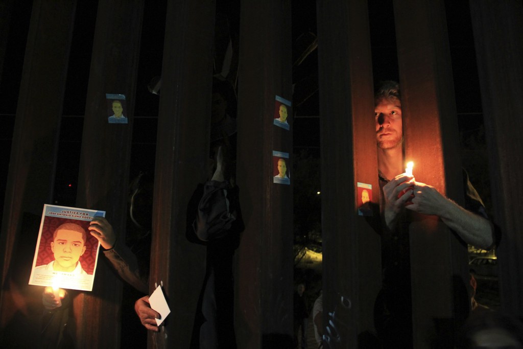 U.S. pro-migration activists hold candles and pictures of late Mexican youth Jose Antonio Elena Rodriguez through the border fence between Mexico and the U.S.