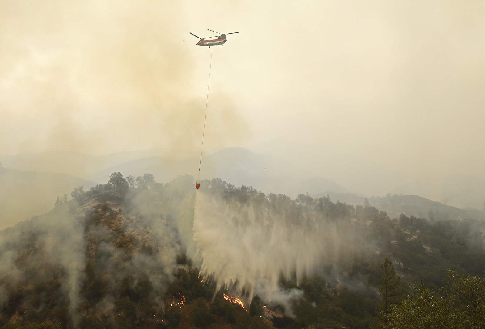 A helicopter drops water on a wildfire in San Andreas on Sept. 12, 2015.