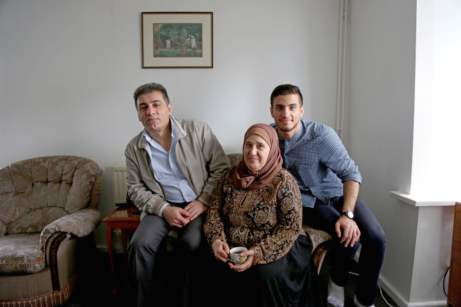 Adel, Haifaa, and their youngest son, Alaa, in their living room in Greater Manchester.