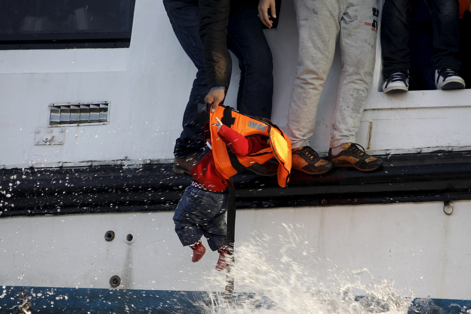 Ein geflüchteter Syrer versucht einen Jungen von einem sinkenden Katamaran an einen Rettungsschwimmer vor der Küste Griechenlands zu übergeben.