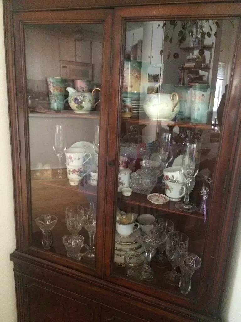 A glass-doored wooden china cabinet filled with china