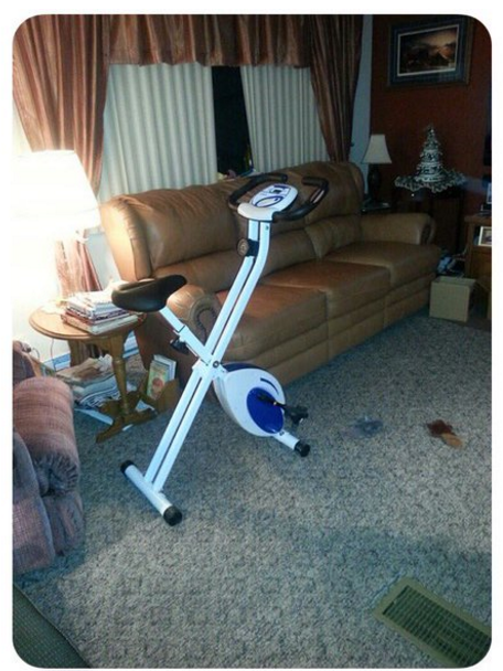 A stationary bike on the rug in a living room in front of an end table and couch