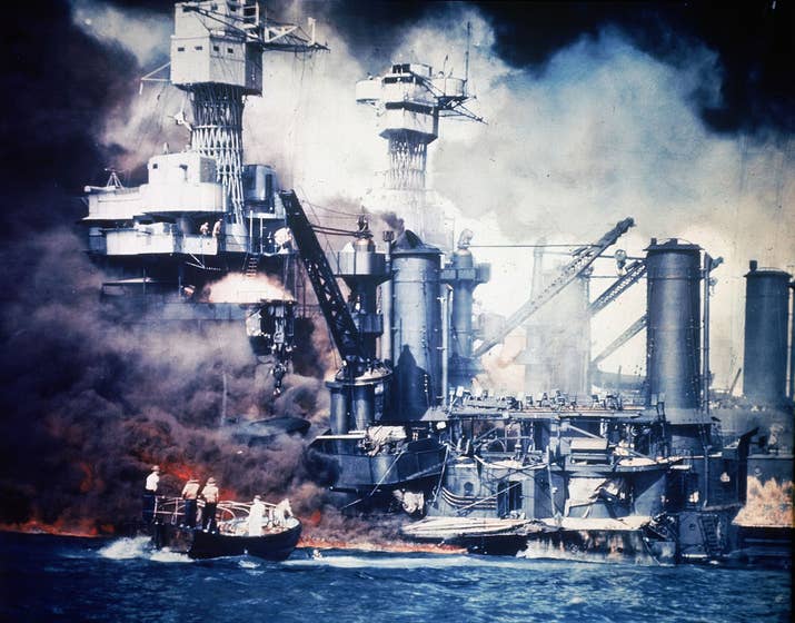 At the scene of the attack, a small boat rescues a USS West Virginia crew member from the water after the Japanese bombing raid.