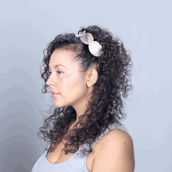 How to get the look:1. Take a small section from behind each ear, begin to twist each one towards the top of your head, secure with pins. 2. From the front section of your hair, pull out a small piece to create a curly bang. Take the remaining hair from that section and twist it back to where the other sections are pinned and secure it in place. 3. Cover the pinned area with a headband.4. Tease the back of your hair for added volume, then finish the front of your look with DevaCurl’s shine spray.