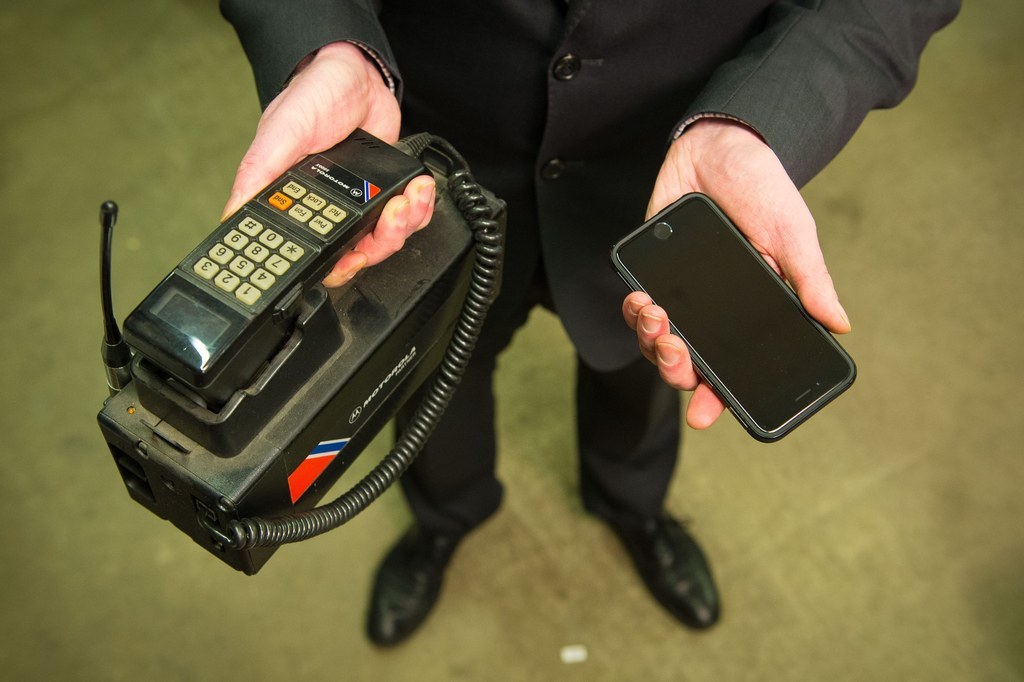 A member of staff holds a Motorola 500X car phone (left) and an Apple iPhone 6.