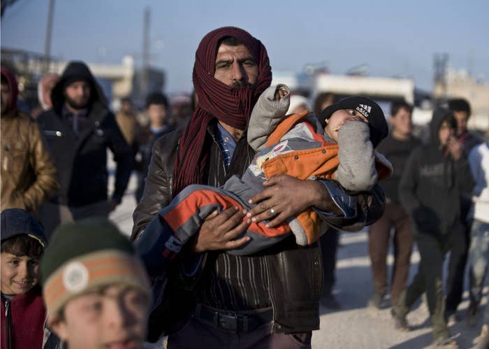 Syrians walk towards the Turkish border at the Bab al-Salam border gate, Syria