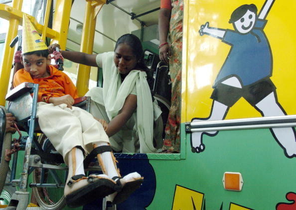 An assistant helps a disabled boy embark Chennai's "Fun Bus," which takes underprivileged children on citywide tours.