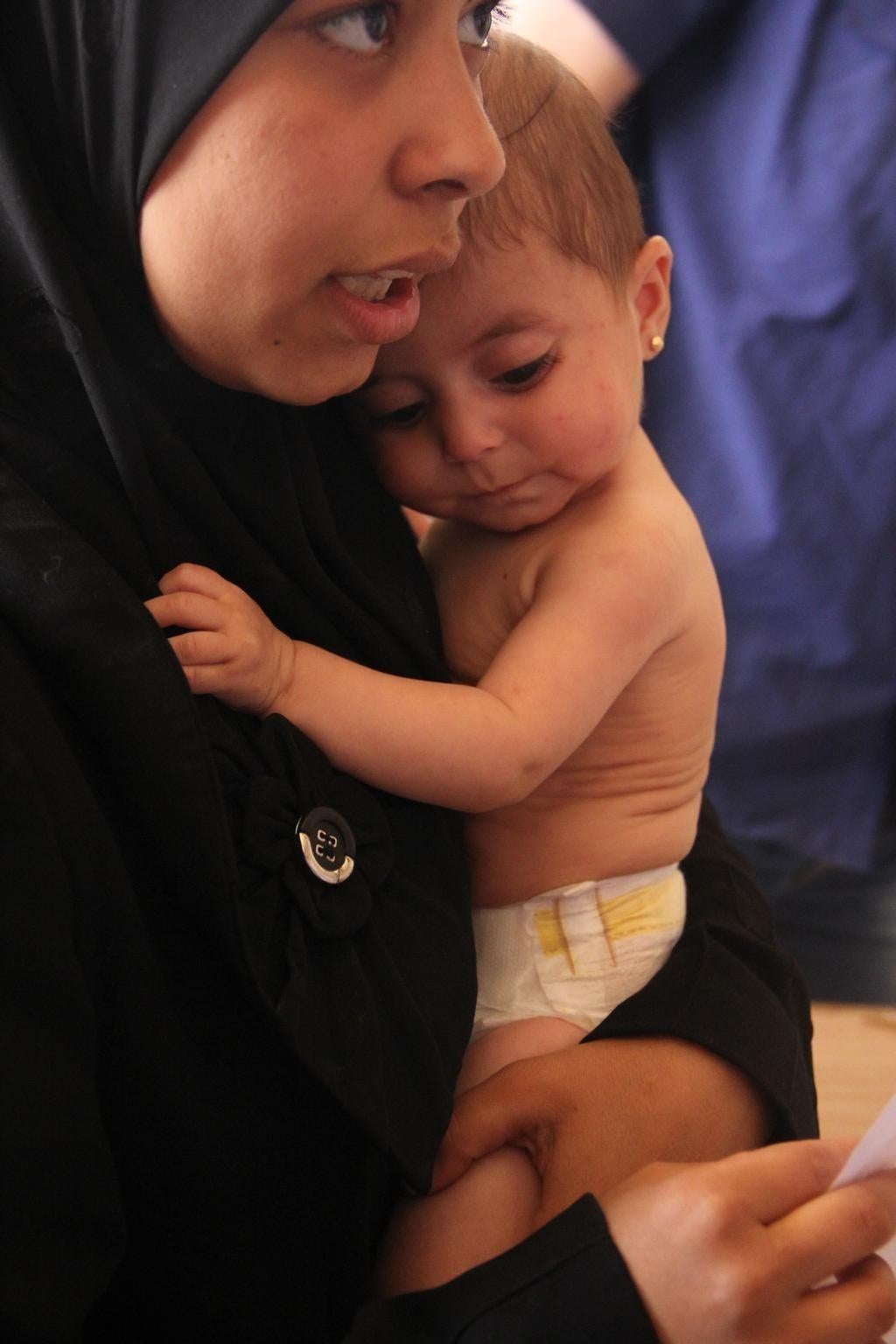 On 11 June 2014 in the Syrian Arab Republic, a woman holds her infant daughter, who underwent treatment for malnutrition, at a UNICEF-supported health centre in Aleppo, the capital of Aleppo Governorate.