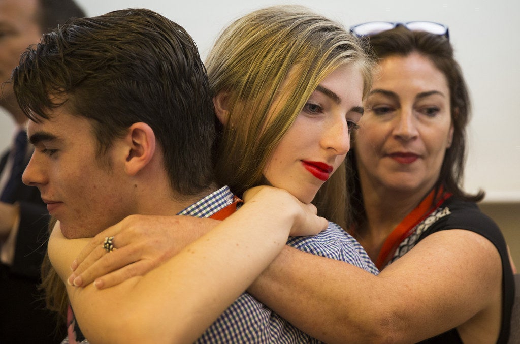15-year-old Georgie embraces her twin brother at Parliament, with mum Rebekah watching on.